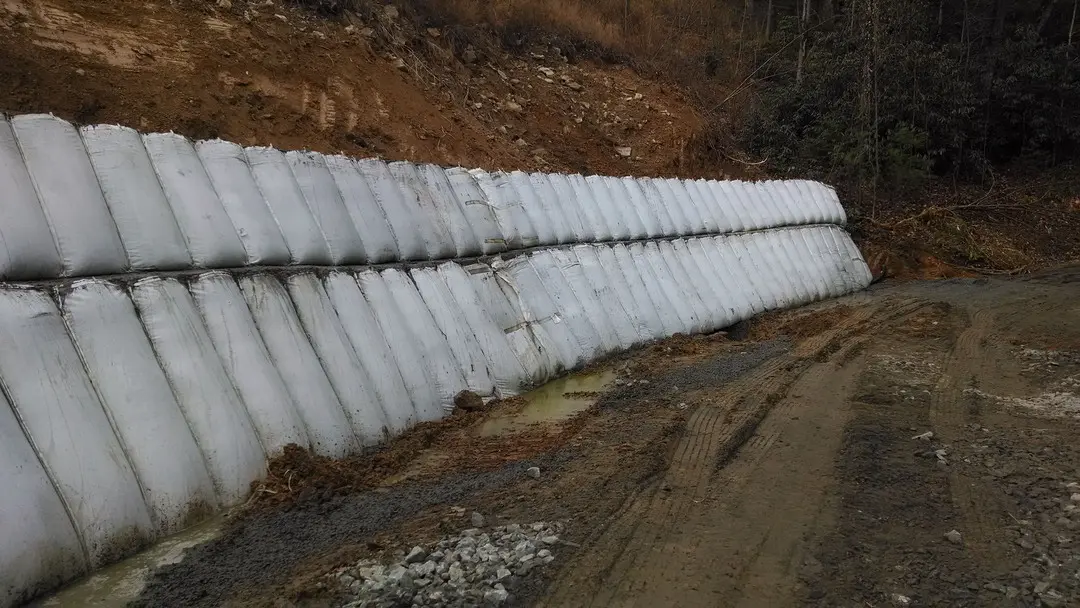 A long fence is made of snow on the side of a road.