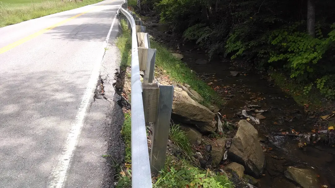 A road with a fallen fence and water