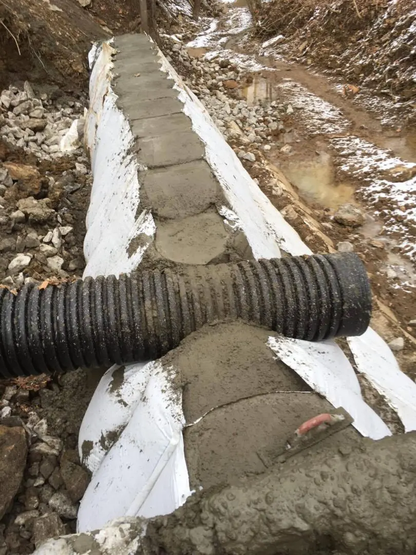 A pipe laying on top of the ground near snow.