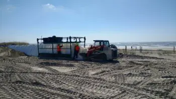 A person standing next to a tractor on top of dirt.