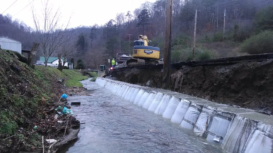 A large truck is in the water near some people.