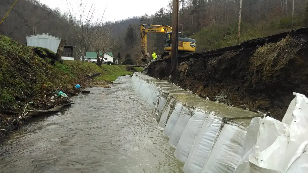 A construction crew working on the side of a river.